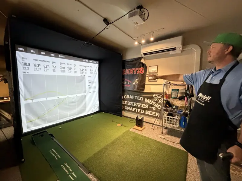 Kyle pointing at GCQuad shot data on the simulator screen